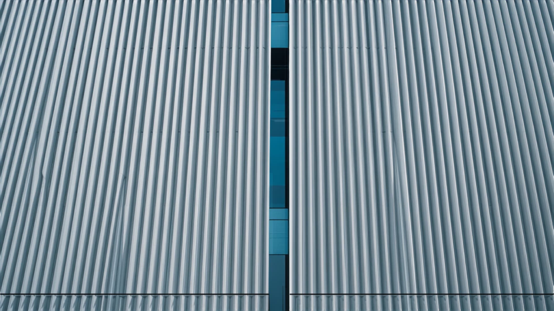 Close-up of a tower facade of vertical louvre fins, with a narrow vertical gap revealing the glazed structure behind.